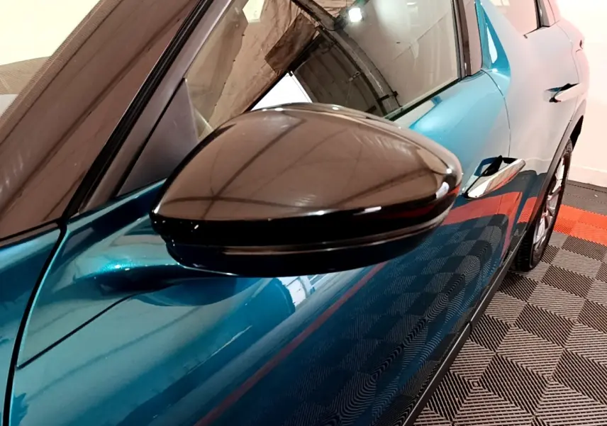Gros plan sur le rétroviseur côté gauche du DS3 Crossback bleu, avec reflet et partie de la portière visible.