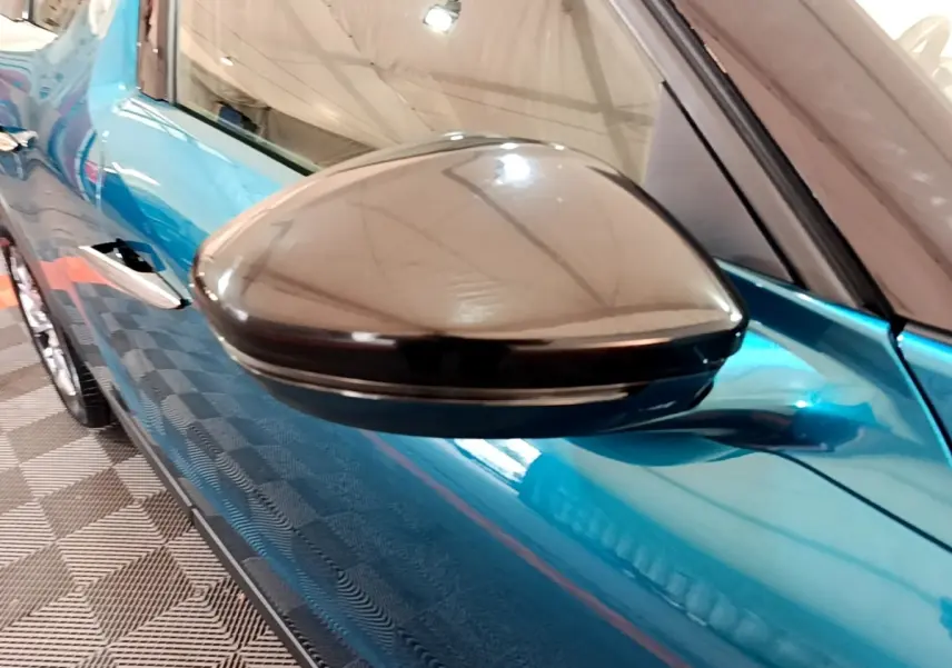 Rétroviseur noir brillant en gros plan côté gauche sur la portière bleu vif d'un DS3 Crossback 2020.