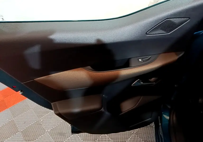 Vue intérieure du panneau de porte côté droit du DS3 Crossback bleu, avec commandes de vitre et haut-parleur intégré.