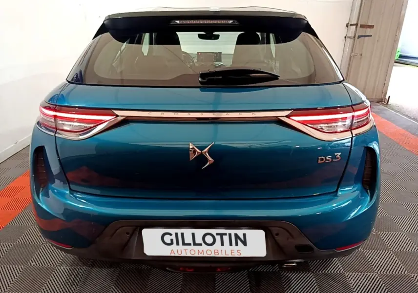 Vue arrière d'une DS3 Crossback bleu métallisé avec feux LED et logo DS bien visible sur un sol à damier.