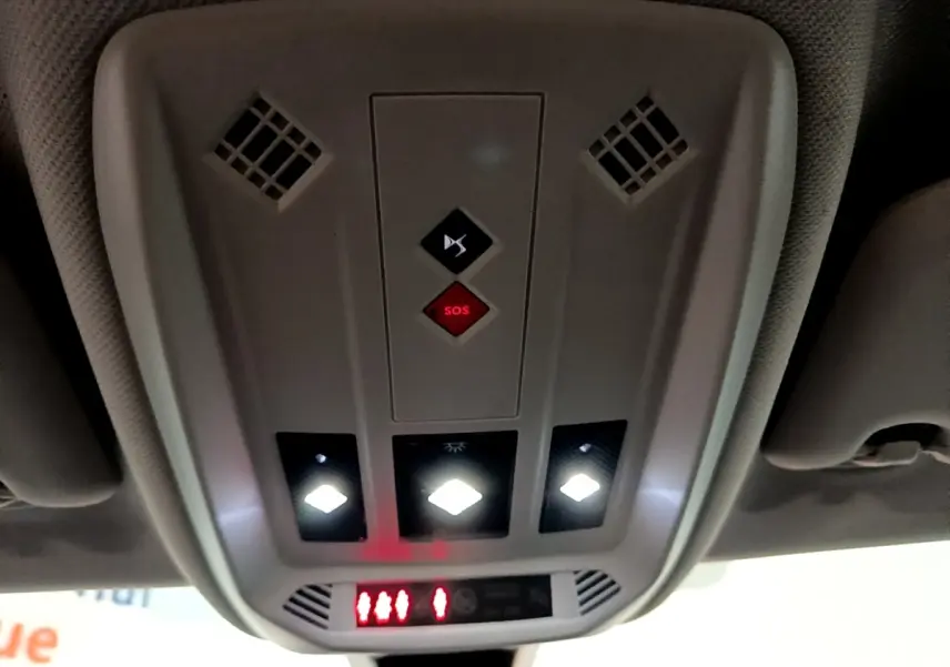 Vue en contre-plongée du plafonnier intérieur gris du DS3 Crossback bleu avec boutons SOS et éclairages LED allumés.