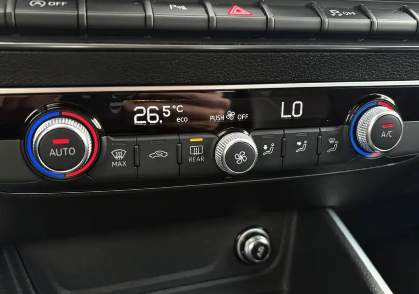 Détail de la console centrale de l’Audi Q2 35 TDI S-Line 2025, montrant la climatisation automatique avec réglages numériques.