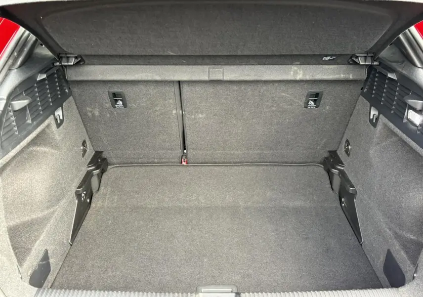 Coffre ouvert d’un Audi Q2 rouge 35 TDI 150 S-Tronic S-Line, montrant l’espace de chargement tapissé de tissu gris.