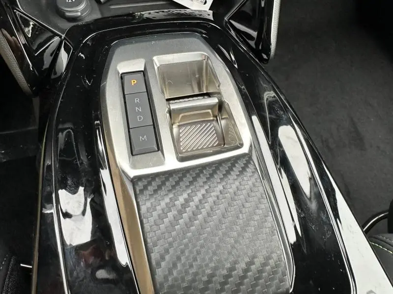 Vue rapprochée de la console centrale noire avec levier de boîte automatique et finition carbone du Peugeot 2008 gris hybride 2025.