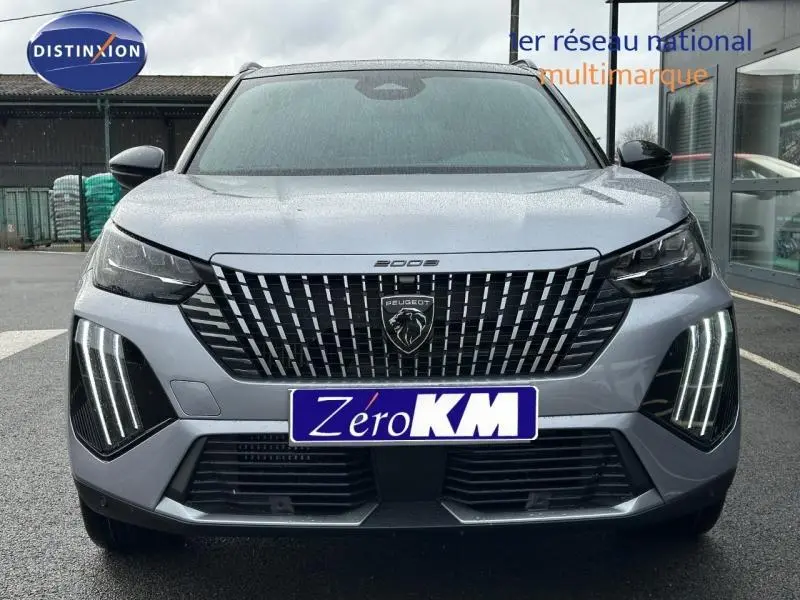 Vue de face du Peugeot 2008 gris 2025 avec calandre noire distinctive et feux LED verticaux allumés.