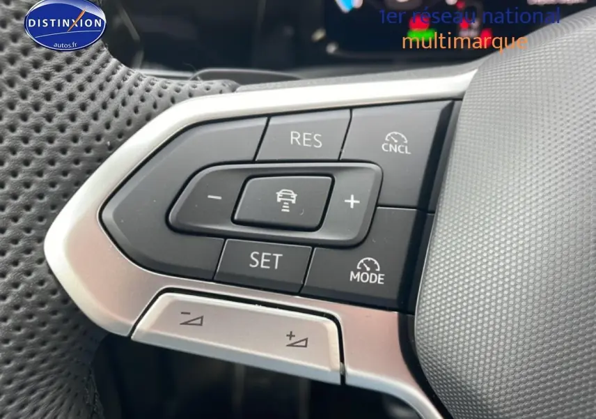 Gros plan sur les commandes de régulateur de vitesse au volant cuir perforé d'une Volkswagen Golf noire 2026.