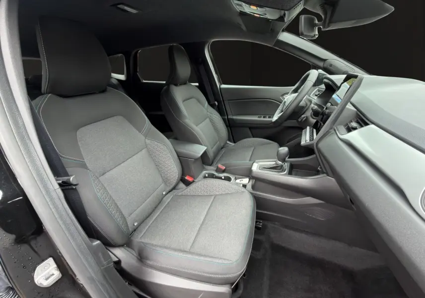 Vue intérieure côté conducteur de la Renault SYMBIOZ 2025, sièges tissu gris avec surpiqûres bleues et tableau de bord moderne.