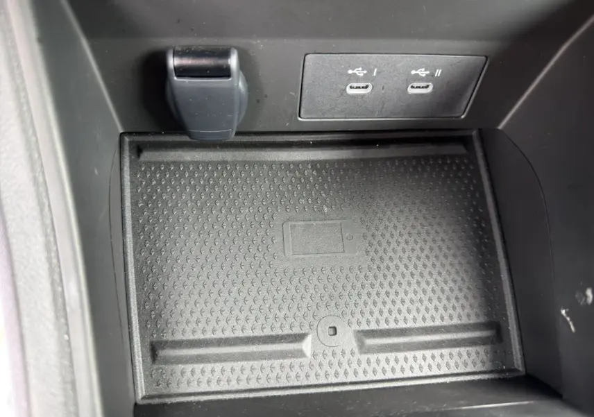 Gros plan sur la zone de recharge sans fil et ports USB-C avant dans l’habitacle noir du Renault Symbioz 2025.