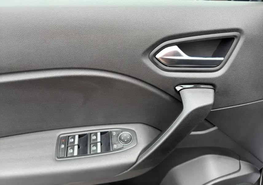 Vue rapprochée de la porte intérieure côté gauche de la Renault Symbioz noire, avec commandes électriques des vitres et poignée argentée.