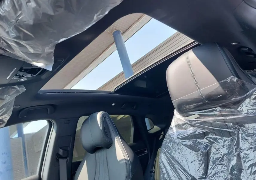 Vue intérieure du toit ouvrant panoramique et des sièges avant gris clair protégés par des housses plastiques sur BYD SEAL U DM-i BOOST 2026.
