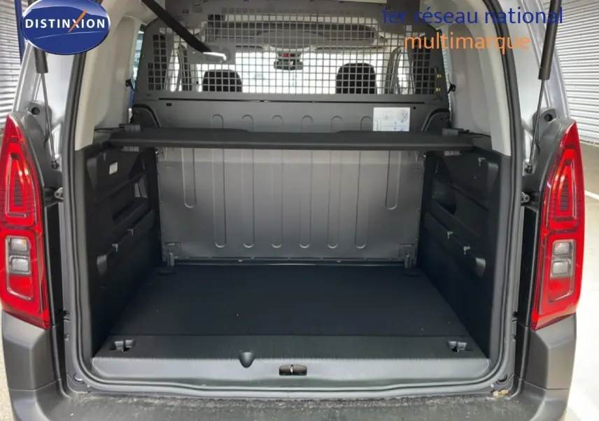 Coffre ouvert d’un Citroën Berlingo gris Artense métal, vue arrière montrant l’espace de chargement et la grille de séparation.