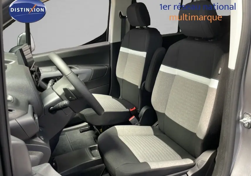 Vue intérieure côté conducteur du Citroën Berlingo gris Artense, sièges tissu bicolore gris et noir, volant multifonction visible.