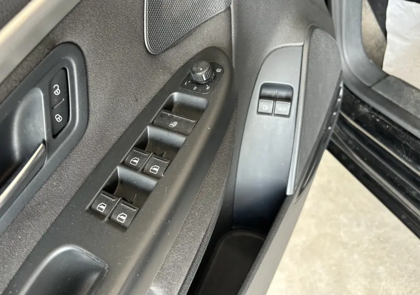 Gros plan sur la commande des vitres et rétroviseurs côté conducteur d'une Volkswagen EOS 2008 en reflet d'argent.