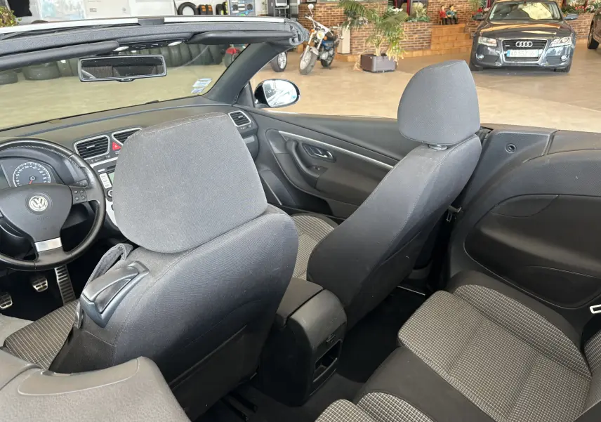 Intérieur du cabriolet Volkswagen EOS 2008, vue arrière montrant les sièges noirs et la planche de bord côté gauche.