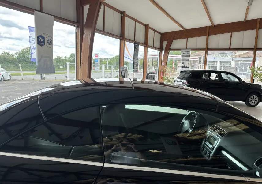 Vue latérale gauche d’un Volkswagen EOS 2.0l TDI 140 ch sportline noir brillant, intérieur visible à travers la vitre.