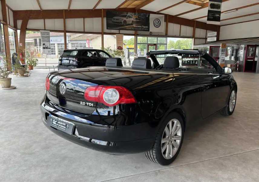 Volkswagen EOS 2.0 TDI noire vue 3/4 arrière droit en cabriolet dans un showroom lumineux.
