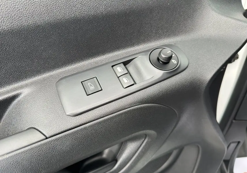 Gros plan sur la commande de réglage des rétroviseurs et vitres côté conducteur d'un Peugeot Partner blanc 2022.