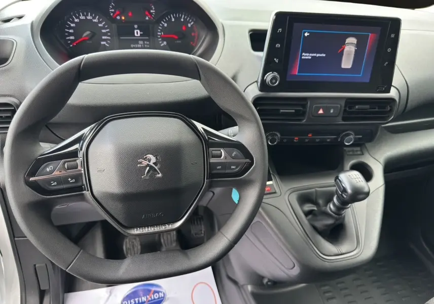 Vue intérieure du tableau de bord du Peugeot Partner 2022 avec volant multifonction et écran tactile central affichant une alerte.