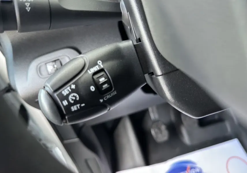 Gros plan sur la commande de régulateur de vitesse noire dans l'habitacle du Peugeot Partner blanc 2022.