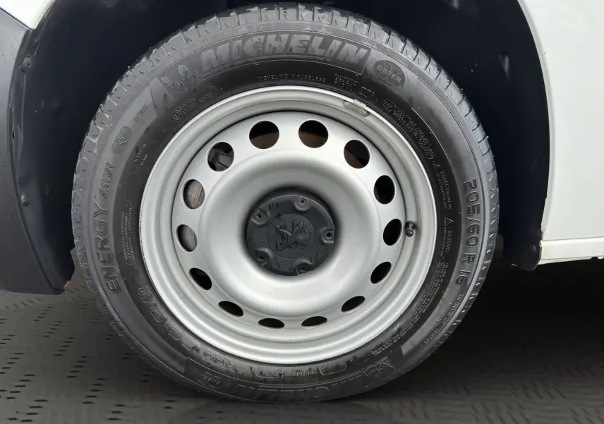 Gros plan sur la roue avant gauche du Peugeot Partner blanc 2022, pneu Michelin Energy Saver avec jante acier grise.
