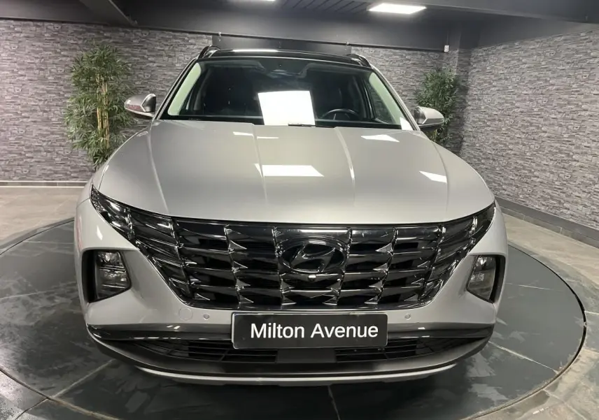 Vue frontale d'un Hyundai Tucson gris métallisé avec calandre noire brillante et phares intégrés.