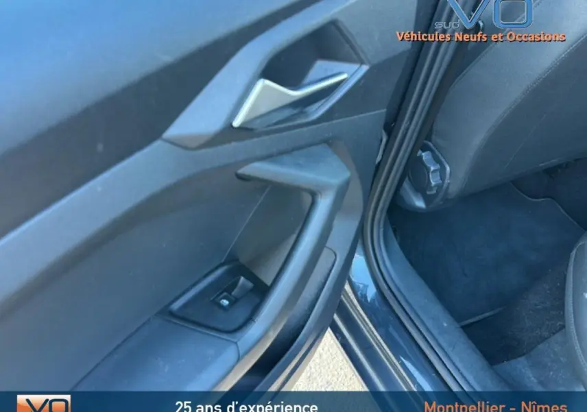 Gros plan sur la portière côté gauche de l'Audi A1 Sportback gris foncé, montrant la poignée et le bouton de vitre électrique.