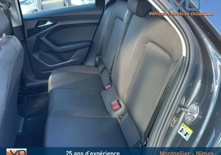 Vue intérieure du siège arrière côté droit de l'Audi A1 Sportback gris foncé avec habillage tissu et ceintures visibles.