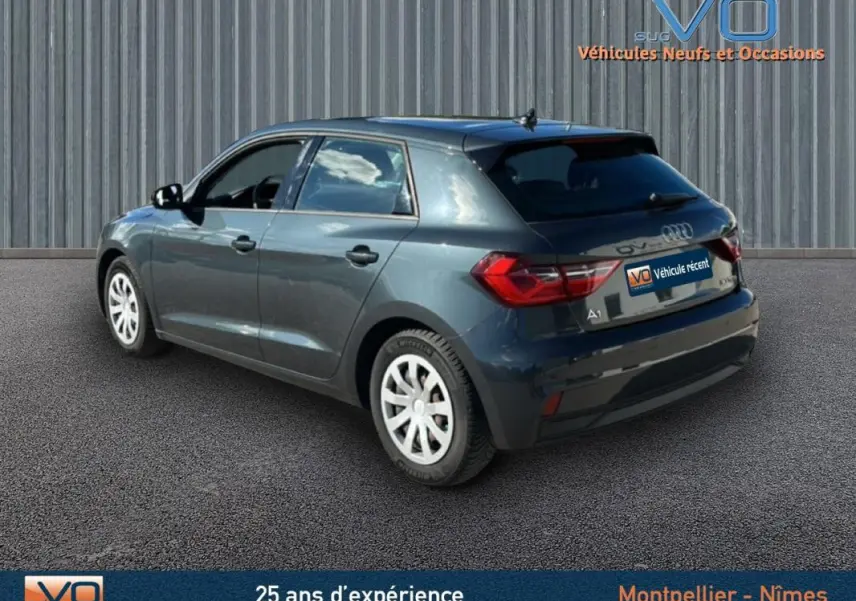 Audi A1 Sportback gris foncé vue 3/4 arrière côté gauche, avec feux arrière et jantes blanches visibles