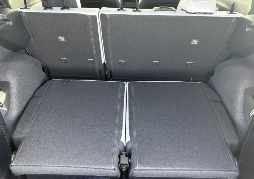 Vue arrière du coffre du Citroën C3 Aircross 2025 avec banquette 3e rang rabattue, intérieur gris foncé et tissu texturé.