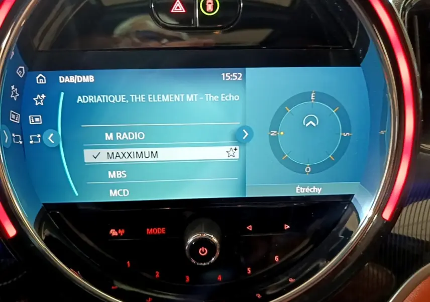 Écran tactile central du tableau de bord bleu de la MINI Countryman Cooper SE avec commandes circulaires et affichage radio.