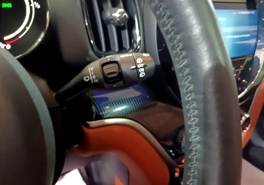 Gros plan sur le volant cuir et la commande d’essuie-glace du MINI Countryman Cooper SE bleu, tableau de bord partiellement visible.