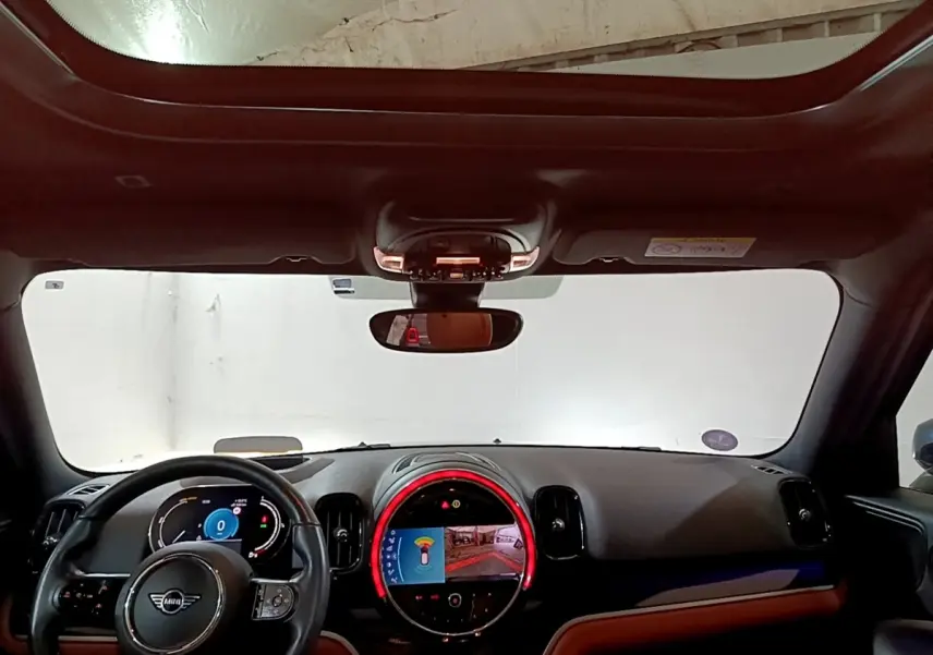 Intérieur du MINI Countryman Cooper SE 2021, vue tableau de bord avec écran central circulaire et volant cuir noir.