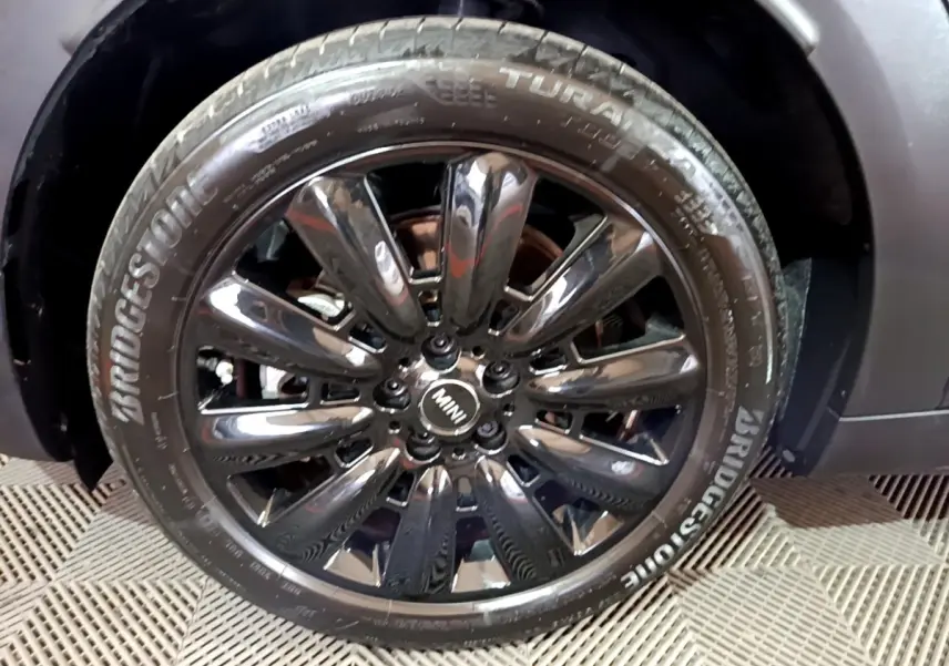 Gros plan sur la jante noire brillante et le pneu Bridgestone d'une MINI Countryman bleu 2021 côté avant droit.