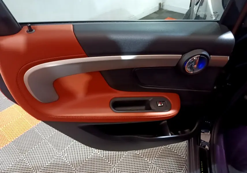 Gros plan sur la porte intérieure côté droit du MINI Countryman 2021, garniture cuir orange et détails argentés.