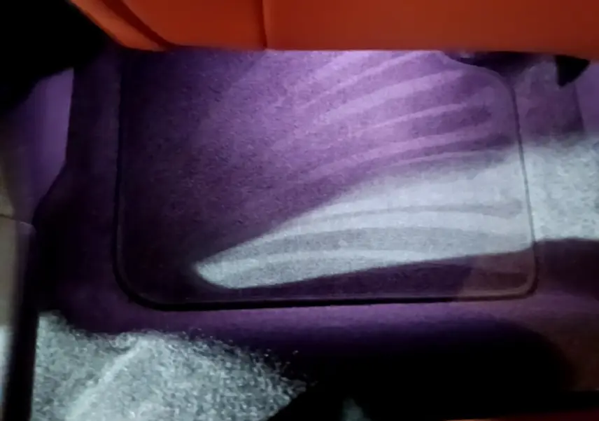 Plancher avant droit intérieur du MINI Countryman bleu 2021 avec tapis de sol et éclairage violet subtil.