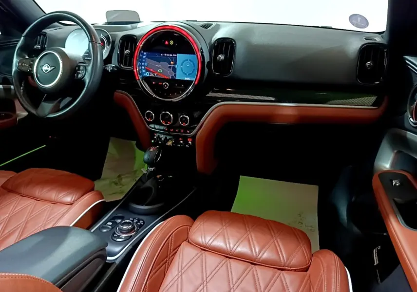 Intérieur avant droit du MINI Countryman Cooper SE avec sièges cuir marron et tableau de bord noir avec écran tactile central.