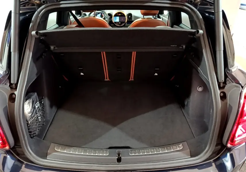 Coffre ouvert vu de l'arrière d'une MINI Countryman Cooper SE bleu, avec banquette arrière et tableau de bord visibles.