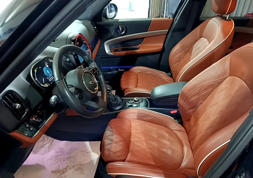 Intérieur côté conducteur du MINI Countryman Cooper SE 2021 avec sièges cuir marron et tableau de bord moderne.