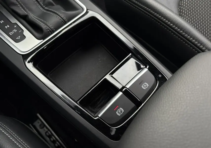 Gros plan sur la console centrale de l'Audi Q2 35 TDI S-Line 2025, montrant la boîte auto et les commandes de frein à main électrique.