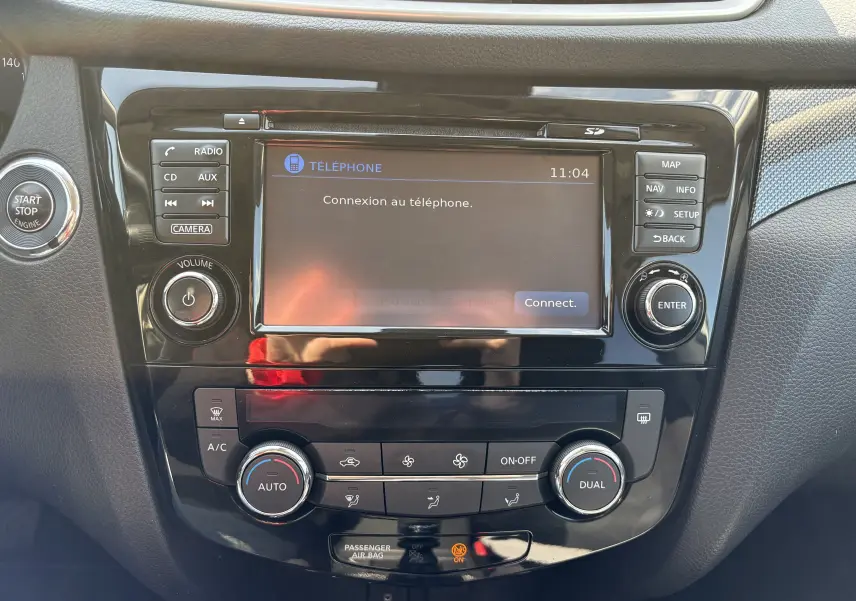 Tableau de bord du Nissan X-TRAIL 2016, vue frontale centrée sur l’écran tactile et les commandes de climatisation.