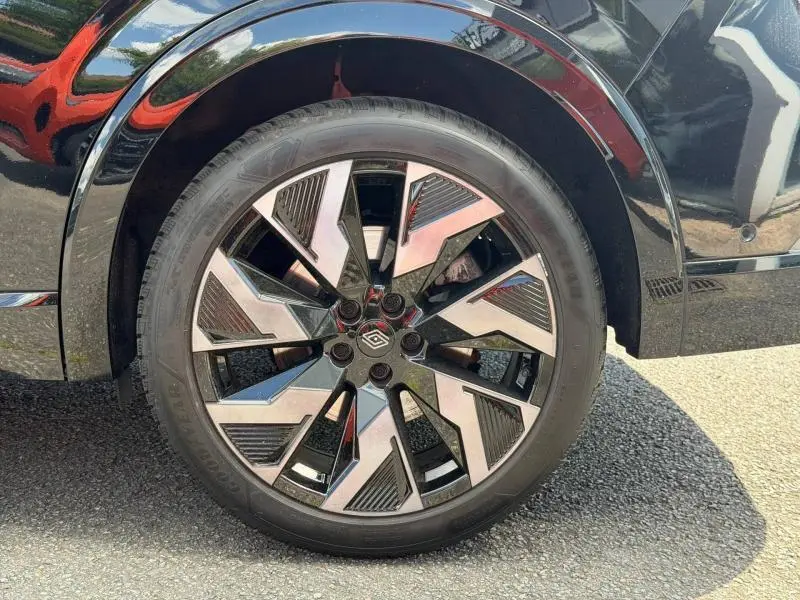 Gros plan sur la roue avant droite du Renault Rafale noir étoilé, avec jante alu au design géométrique bicolore.