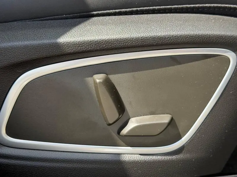 Détail des commandes de réglage de siège en plastique noir sur panneau intérieur noir d’une Renault Rafale 2025.
