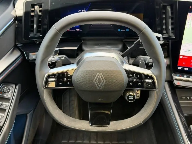 Vue rapprochée du volant multifonction noir de la Renault Rafale 2025 avec commandes intégrées et écran numérique en arrière-plan.