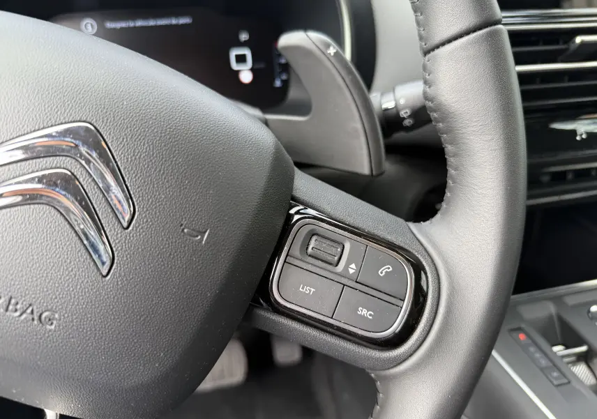 Gros plan sur le volant noir du Citroën C5 Aircross 1.5 HDi 130, avec commandes audio et régulateur visible.