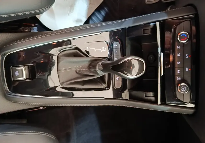 Gros plan sur la console centrale noire brillante de l'Opel Grandland X 1.5 Diesel 130 GS Line avec levier de boîte auto et commandes climatisation.