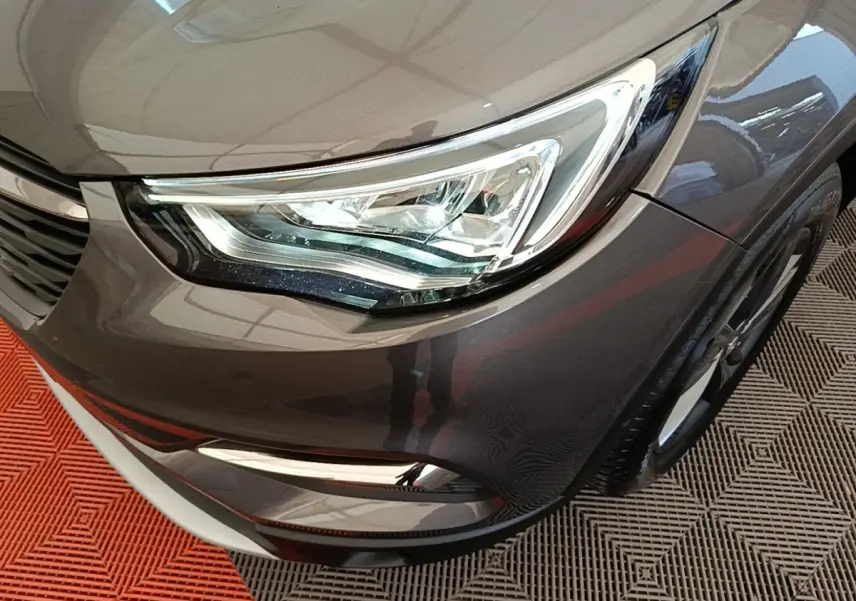 Gros plan sur l'avant droit gris foncé de l'Opel Grandland X 2021, mettant en valeur le phare LED et la calandre.