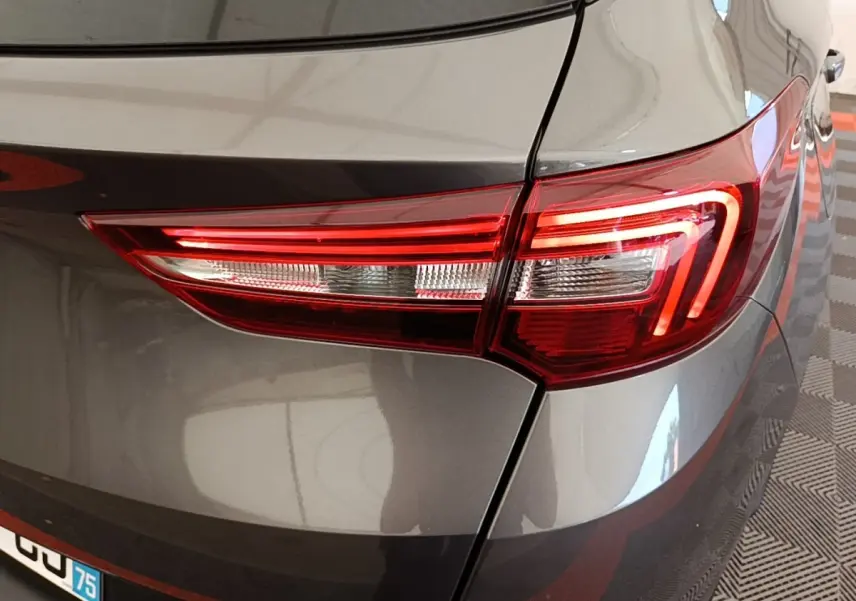 Gros plan sur le feu arrière droit rouge et blanc d’un Opel Grandland X gris foncé, vue arrière côté droit.