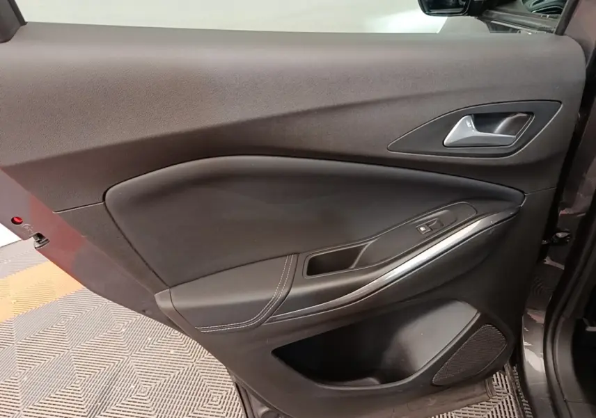 Vue intérieure de la porte avant gauche de l’Opel Grandland X gris foncé avec poignée alu et commande de fenêtre.