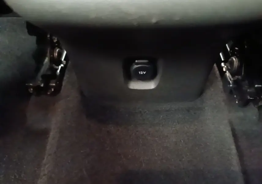 Prise 12V noire en gros plan sous la console centrale, intérieur sombre de l’Opel Grandland X gris foncé.