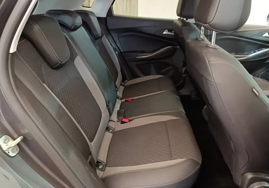 Vue latérale intérieure sur la banquette arrière gris foncé de l’Opel Grandland X avec appuie-têtes et ceintures visibles.
